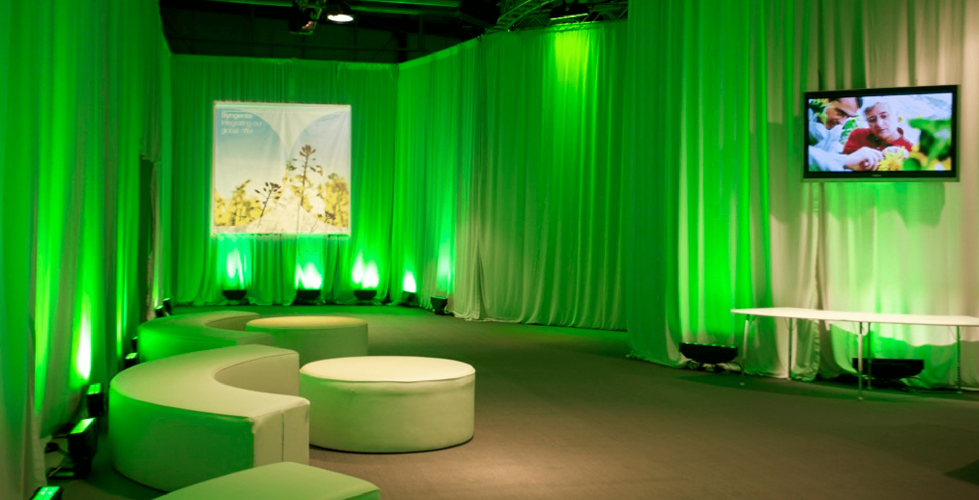 Entrance to meetings space Product displays and green lit white drape.