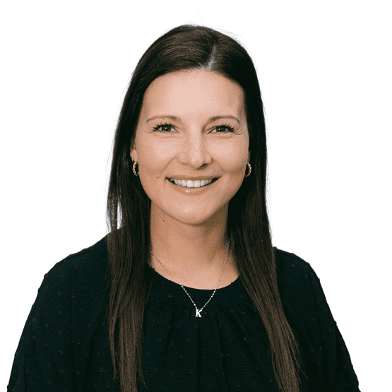 Smiling woman with long dark hair wearing a black blouse and gold hoop earrings, photographed against a white background.