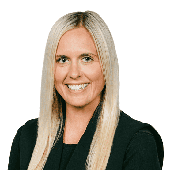 Professional headshot of a smiling blonde woman in a black blazer against a white background.