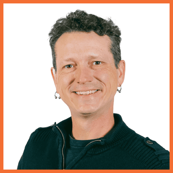 Smiling man with short curly hair in a dark zip sweater, facing the camera against a white background with an orange border edge.