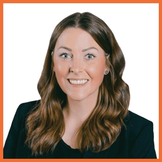 Professional headshot of a smiling woman with long brown wavy hair, wearing a black blazer, against a white background.